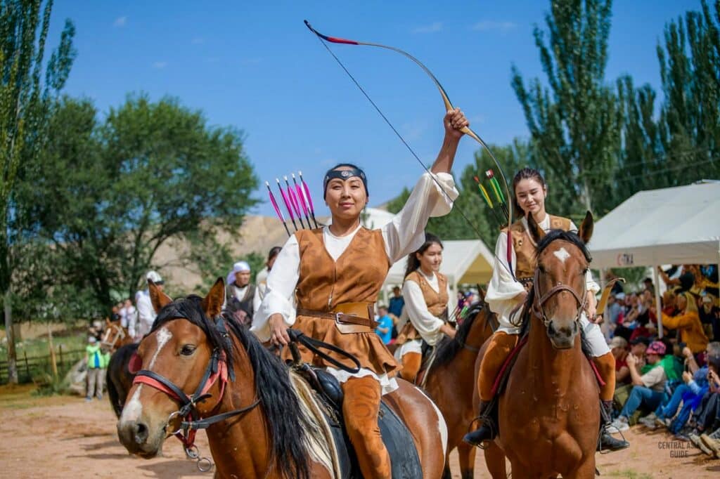 Kyrgyz women riding horses with bows during salburun festival