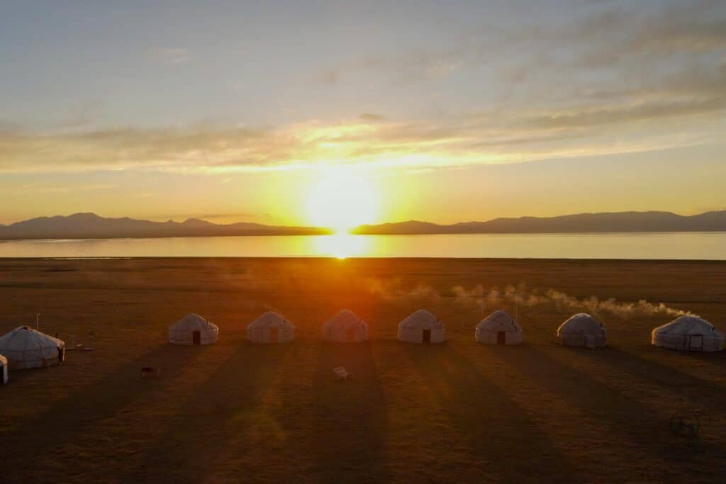 Sunset casting shadows of yurts in Song Kul Lake